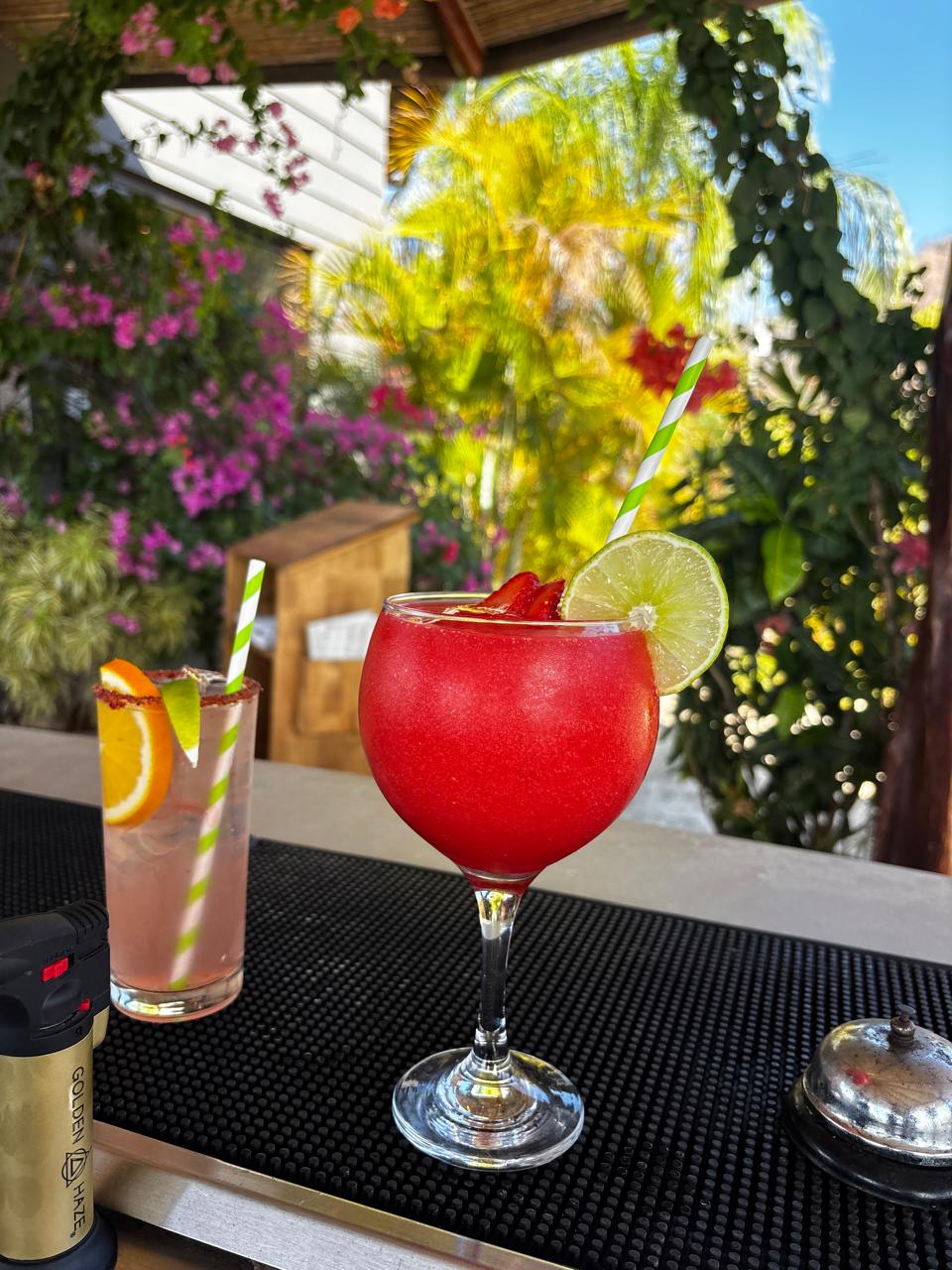 Daiquirí de fresa con rodaja de limón junto a un coctel cítrico en la barra